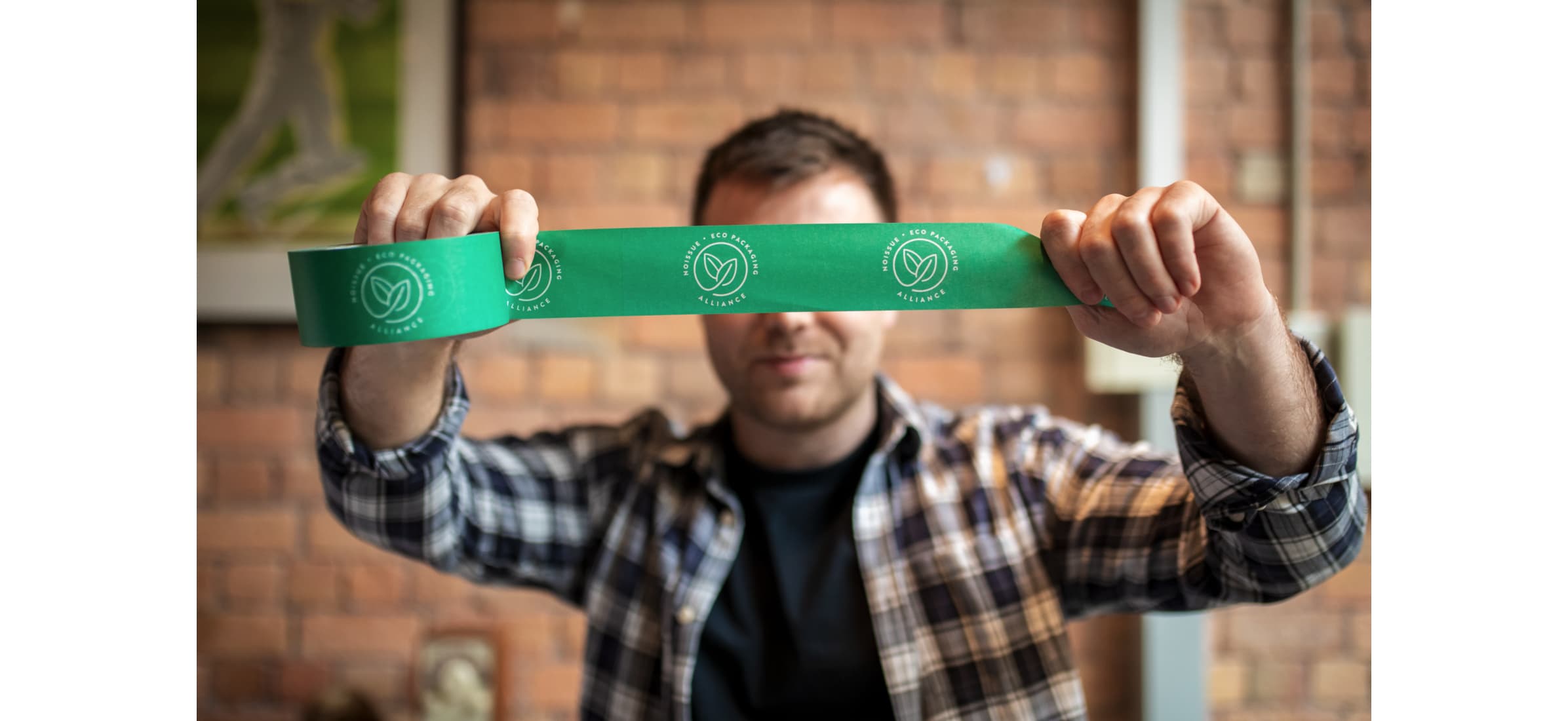Business owner Josh Bowden holds up a line of compostable tape. 